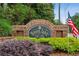 Entrance sign for Towne Lake Hills community, beautifully landscaped with colorful bushes and a patriotic American flag at 107 W Point Trl, Woodstock, GA 30189