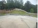 Concrete patio with a retaining wall, sloping backyard, and tall trees in the background at 5421 Skylar Creek Ln, Buford, GA 30518
