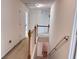 Hallway with carpeted floors, a staircase with wooden railing, and multiple doors leading to different rooms at 5421 Skylar Creek Ln, Buford, GA 30518