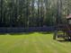 Spacious backyard with green grass, a wooded backdrop, and a play structure at 1952 Azalea Dr, Lawrenceville, GA 30043