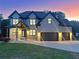 Elegant brick home with dark trim, a well-manicured lawn, and a three-car garage illuminated at dusk at 1952 Azalea Dr, Lawrenceville, GA 30043