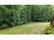 Lawn with a wooded backdrop, highlighting the natural beauty of the property at 4995 Aviary Nw Dr, Acworth, GA 30101