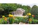 Landscaped backyard featuring colorful flowers, a serene pond, and a view of the home's exterior at 4995 Aviary Nw Dr, Acworth, GA 30101