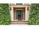 Elegant front door with glass detailing, flanked by brick columns and manicured evergreens at 4995 Aviary Nw Dr, Acworth, GA 30101