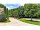 Long driveway leading to a landscaped yard with evergreens, flowering trees, and a well-manicured lawn at 4995 Aviary Nw Dr, Acworth, GA 30101