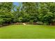 Lush backyard with a green lawn, manicured garden beds, and mature trees at 5365 Vendelay Ln, Cumming, GA 30040