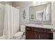 Well-lit bathroom with granite countertop vanity, decorative mirror, and shower with white curtain at 5365 Vendelay Ln, Cumming, GA 30040