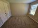 Bedroom with carpet flooring and neutral colored walls with a window and double door closet at 1021 Rock Elm Dr, Auburn, GA 30011
