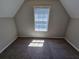 Cozy carpeted room with an A-frame ceiling and a window with light coming through at 1021 Rock Elm Dr, Auburn, GA 30011