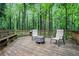 Outdoor wooden deck featuring a rustic bench, chairs, and a fire pit, surrounded by verdant trees at 1879 Beaver Dam Ne Ln, Marietta, GA 30062