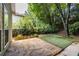 Beautiful backyard with lush landscaping, stone patio, artificial lawn, and mature trees at 1100 Ashbury Dr, Decatur, GA 30030