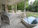 Covered porch with wicker furniture, blue accents, ceiling fan, and swing overlooking the serene, tree-filled backyard at 1811 Murdock Rd, Marietta, GA 30062