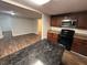 Spacious kitchen with dark wood cabinets, an island with a granite top, and stainless steel appliances at 1095 S Burnt Hickory Rd, Douglasville, GA 30134
