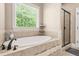 Luxurious bathroom featuring a soaking tub, glass-enclosed shower, and serene views through a large window at 229 Primstone Way, Mcdonough, GA 30253