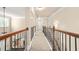 Hallway upstairs with carpet, black metal and wood railing, arched doorway, and overhead lighting at 229 Primstone Way, Mcdonough, GA 30253