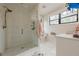 Bright bathroom featuring a glass shower, white tile, marble floors, and a white vanity by a window at 6301 New Bethany Rd, Buford, GA 30518