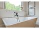 Close up on modern white soaker bathtub with black faucet and view to outdoors at 6301 New Bethany Rd, Buford, GA 30518