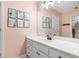 Well-lit bathroom with pale pink walls, white cabinets, and framed artwork on the wall at 9595 Rod Rd, Alpharetta, GA 30022