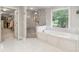 Luxurious primary bathroom with a soaking tub, walk-in shower, and access to the walk-in closet at 9595 Rod Rd, Alpharetta, GA 30022