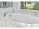 Bright bathroom featuring a white jacuzzi tub with marble tile and a window view at 9595 Rod Rd, Alpharetta, GA 30022