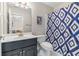 Stylish bathroom with blue and white shower curtain, white tile floor, and modern vanity at 9595 Rod Rd, Alpharetta, GA 30022