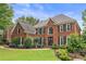 Traditional two-story brick home with manicured lawn, landscaping and basketball hoop in driveway at 9595 Rod Rd, Alpharetta, GA 30022