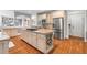 Kitchen island with cooktop, seating, wine rack, stainless refrigerator, and hardwood flooring at 9595 Rod Rd, Alpharetta, GA 30022