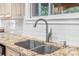 Granite countertop surrounding double basin sink and chrome faucet with white subway tile backsplash at 9595 Rod Rd, Alpharetta, GA 30022