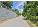 Concrete path surrounded by lush greenery and trees under a blue sky with scattered clouds on a sunny day at 1268 Ladd Sw St, Atlanta, GA 30310