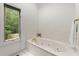 Soaking tub with jets beside window offering wooded view in neutral, airy bathroom at 1678 Rabke Rd, Canton, GA 30114