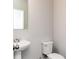 A powder room featuring a toilet and a pedestal sink with faucet and mirror at 2971 Beaconwood Ct, Lawrenceville, GA 30043