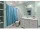 Bright, mint-green bathroom featuring a shower with blue curtain, white vanity and open shelves at 6160 Overleaf Ter, Cumming, GA 30040