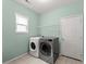 Laundry room with tile floors, washer, dryer, window, and white door at 6160 Overleaf Ter, Cumming, GA 30040