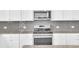 Detailed view of a kitchen with a stainless steel stove, microwave, and light gray subway tile backsplash at 3455 Jasmine Sw Way, Atlanta, GA 30331