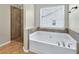 Bright bathroom featuring a soaking tub under a window and a glass-enclosed shower at 3975 Silverthorn Trce, Cumming, GA 30028