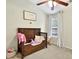 Bedroom boasting a wooden crib, sloped ceiling, and a window dressed with curtains at 3975 Silverthorn Trce, Cumming, GA 30028