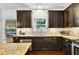 Modern kitchen featuring dark wood cabinets, granite countertops, stainless steel appliances and tiled backsplash at 3975 Silverthorn Trce, Cumming, GA 30028