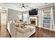 Inviting living room featuring large sectional, fireplace, large TV and sunlit windows with neutral curtains at 3975 Silverthorn Trce, Cumming, GA 30028