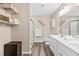 Neutral-toned bathroom with double sink vanity, glass enclosed shower, and shelving unit for storage at 6065 Crescent Landing Dr, Cumming, GA 30028