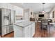 Open concept kitchen with granite island, dining area, stainless steel fridge, and white cabinets at 6065 Crescent Landing Dr, Cumming, GA 30028