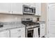 Close-up of stainless steel range, microwave and granite counters with white cabinets and wood floors at 6065 Crescent Landing Dr, Cumming, GA 30028