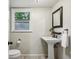 Clean bathroom with white pedestal sink, modern fixtures, and a dark framed mirror at 2516 Cherry Hill Ln, Atlanta, GA 30360