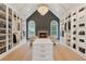 Large walk-in closet with custom shelving, island, hardwood floors, and modern chandelier and adjacent sitting area at 5705 Registry Oaks Se Ln, Mableton, GA 30126