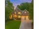 Charming two-story stone home with a manicured lawn and two-car garage at dusk at 5705 Registry Oaks Se Ln, Mableton, GA 30126
