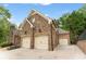 Stone facade three-car garage with carriage doors and concrete driveway at 5705 Registry Oaks Se Ln, Mableton, GA 30126