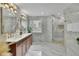 Bright bathroom with marble tile, double vanity with gold fixtures and a glass-enclosed shower with mosaic floor at 1701 English Ivey Nw Ln, Kennesaw, GA 30144