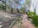 Backyard brick path leading to an outdoor pergola seating area surrounded by mature trees at 5090 Eubanks Rd, Woodstock, GA 30188