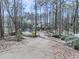 Long driveway leading to a light-colored home surrounded by a lush, wooded landscape at 5090 Eubanks Rd, Woodstock, GA 30188