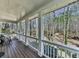 Relaxing covered porch with wooden flooring and white columns offering serene views of nature at 5090 Eubanks Rd, Woodstock, GA 30188