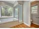 Bright bathroom features a soaking tub under a window and a glass-enclosed shower stall at 80 Surrey Chase Drive, Social Circle, GA 30025